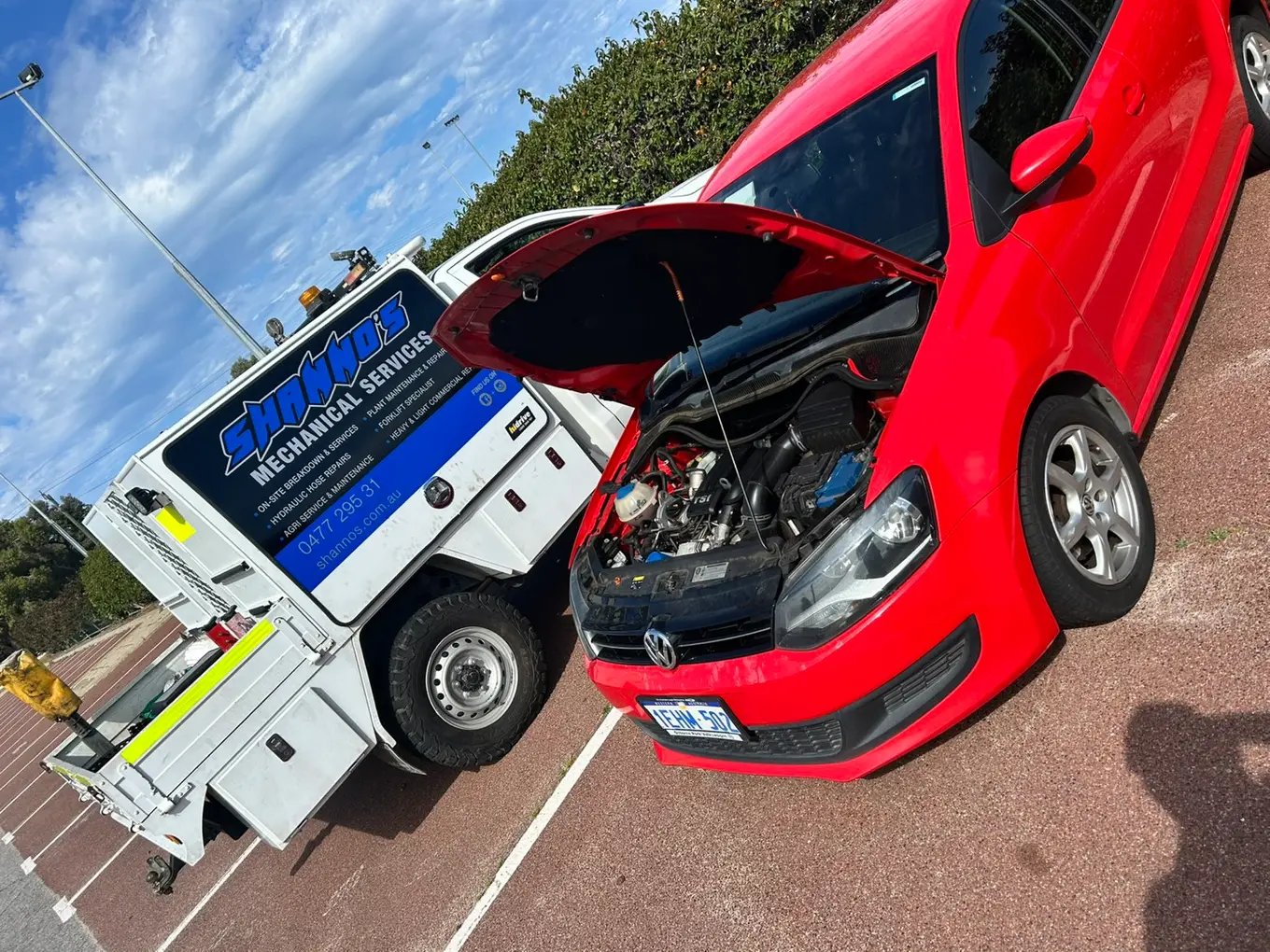 A red Volkswagen hatchback with the bonnet up at the roadside beside a Shanno&rsquo;s service ute